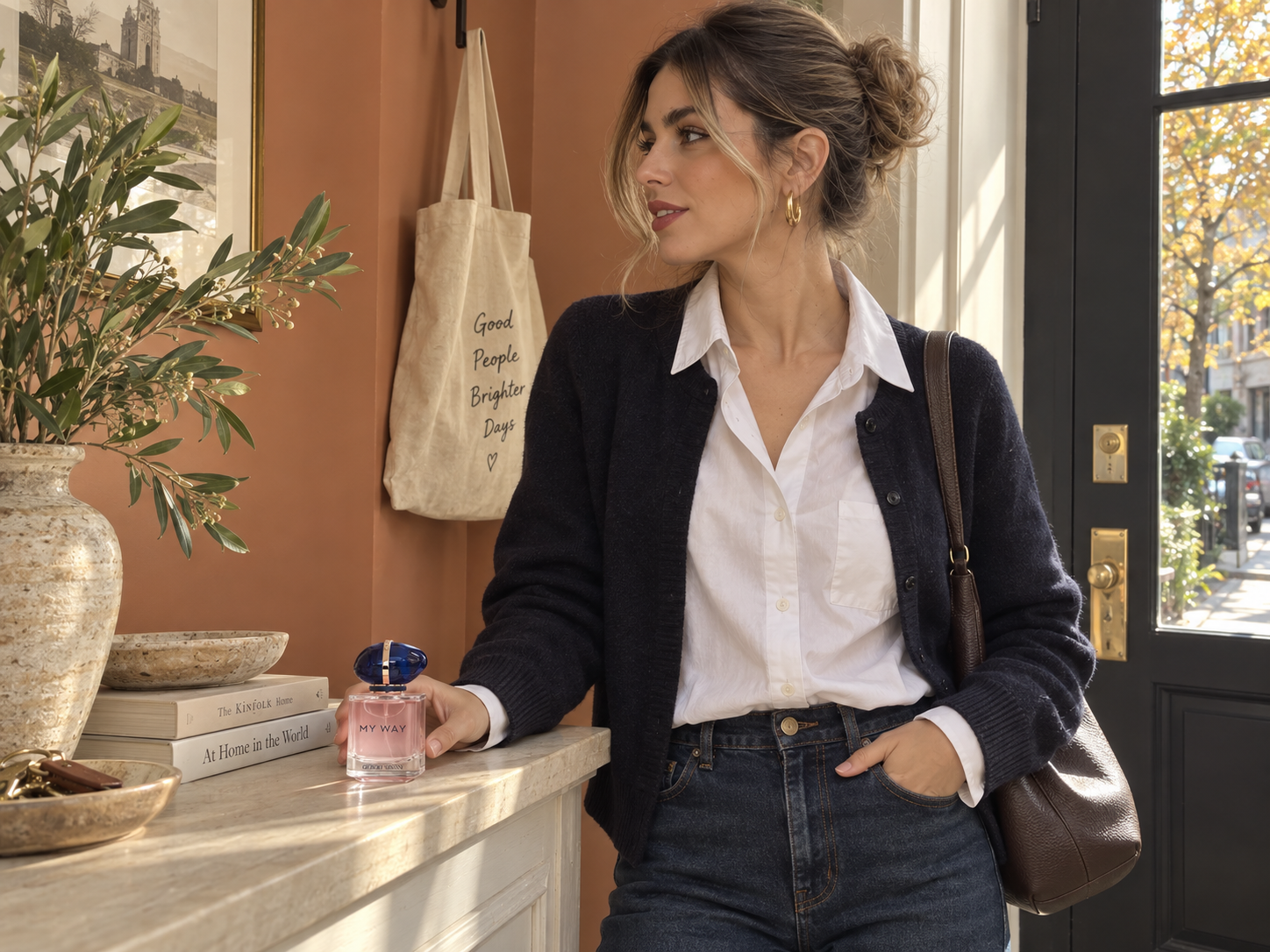 A woman in a white shirt and navy cardigan beside an Armani My Way perfume bottle on an apartment entry console